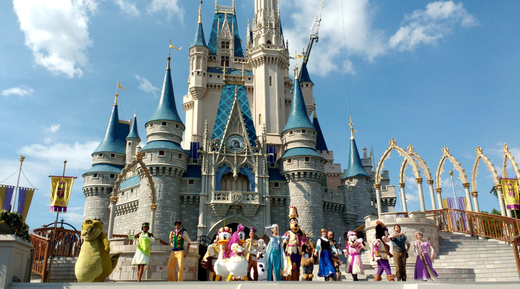 Magic Kingdom em um dia ensolarado, com os personagens Disney fazendo um show em frente a ele